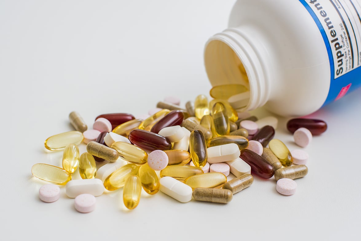 Various colorful pills and capsules spilled from a supplement bottle Various colorful pills and capsules spilled from a supplement bottle